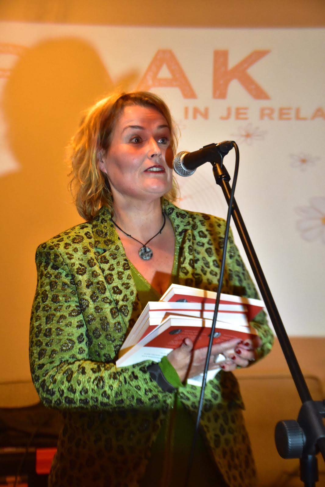 Barbara Veldt spreekt voor het RAAK-banner met haar boek in de hand